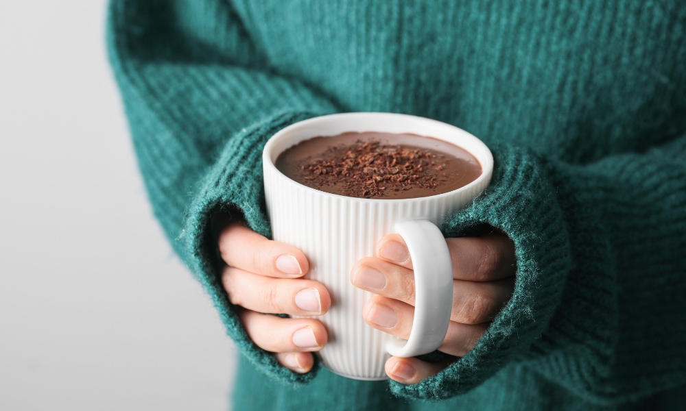 Hands holding a warm mug of hot chocolate, offering a cozy and comforting moment during the holiday season at the office.